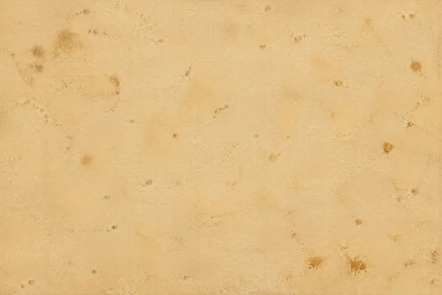 Ochre old paper texture with scattered reddish-brown foxing spots and uneven age marks.